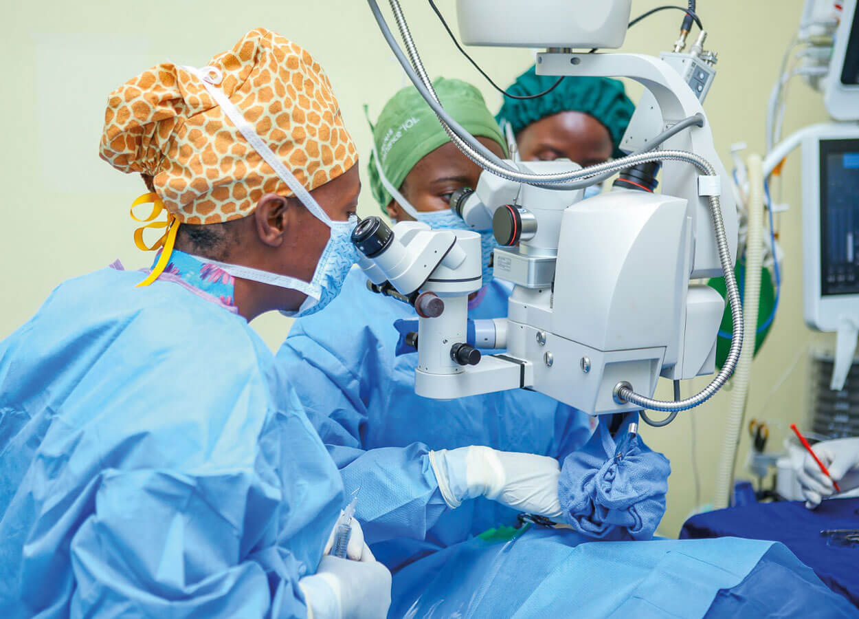 Photo shows Dr Moonga observing Dr Mathe operate.